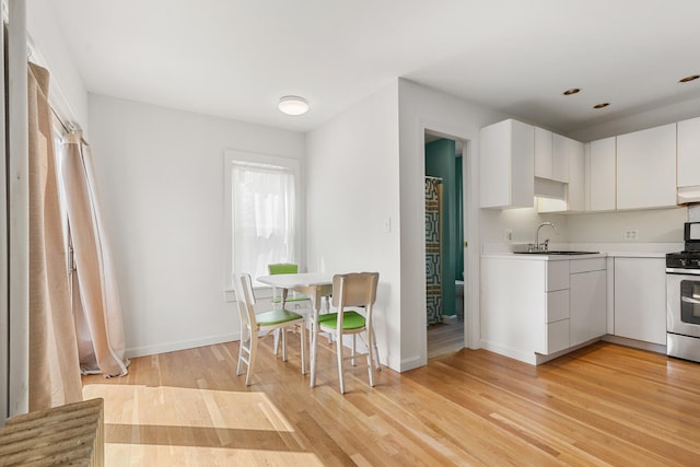 104R Homes Ave, Boston, MA 02123 - kitchen with a sink, stainless steel range with gas cooktop, white cabinetry, light countertops, and light wood-style floors