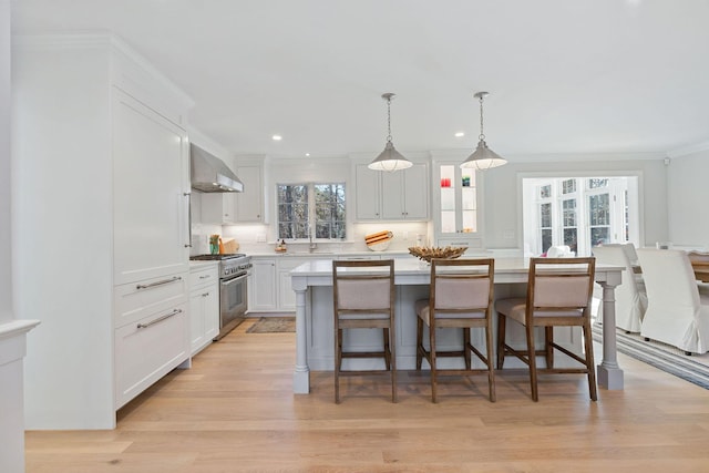 kitchen with white cabinets, a center island, high end range, and wall chimney exhaust hood