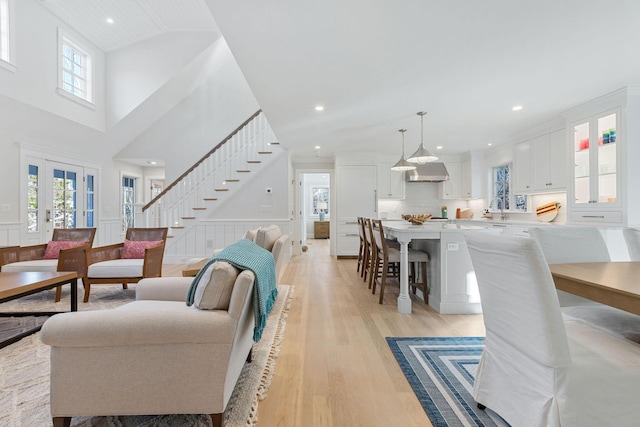 living room with sink, light hardwood / wood-style flooring, and a towering ceiling