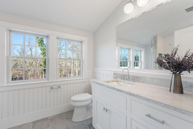 bathroom with toilet, vanity, and vaulted ceiling