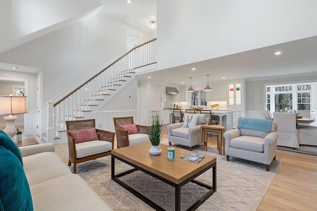 living room featuring crown molding, light hardwood / wood-style flooring, and a high ceiling