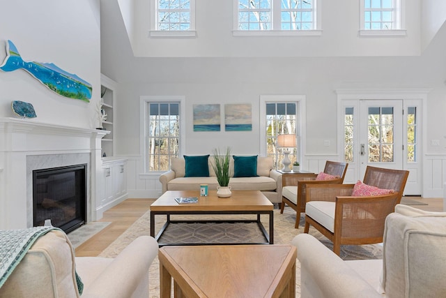 living room featuring built in features, a towering ceiling, and light wood-type flooring