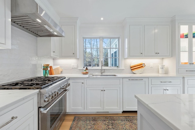 kitchen featuring exhaust hood, white cabinetry, and high end stainless steel range