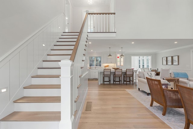 staircase with wood-type flooring and crown molding