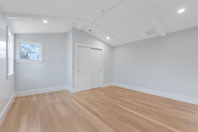 spare room with lofted ceiling with beams and light wood-type flooring