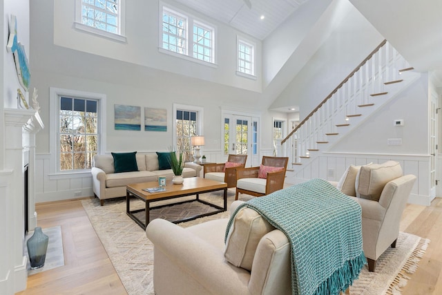 living room featuring french doors, light hardwood / wood-style flooring, and a towering ceiling