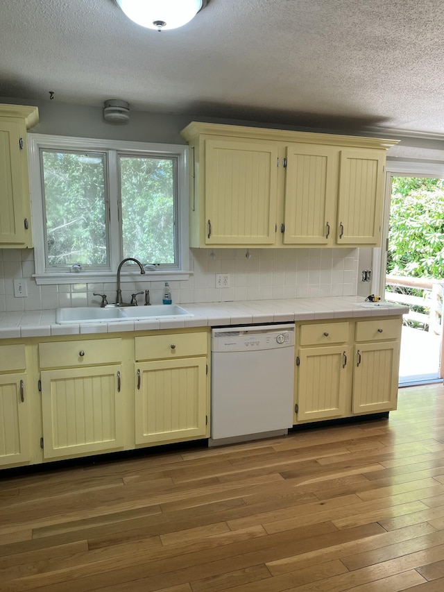 12 Pine Ter, East Sandwich, MA 02537 - kitchen with dishwasher, tile countertops, a textured ceiling, light wood finished floors, and decorative backsplash