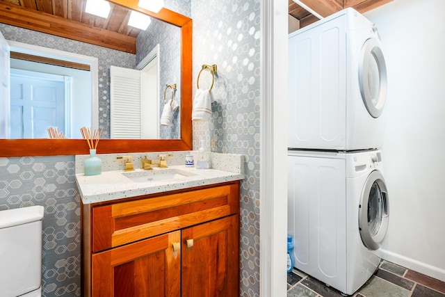 11 Allyn Ln, Barnstable, MA 02630 - bathroom featuring baseboards, toilet, stacked washing maching and dryer, vanity, and wallpapered walls