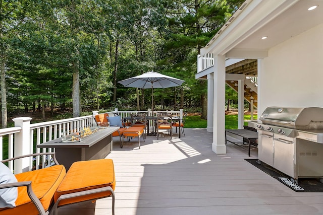 wooden terrace with an outdoor fire pit and a grill