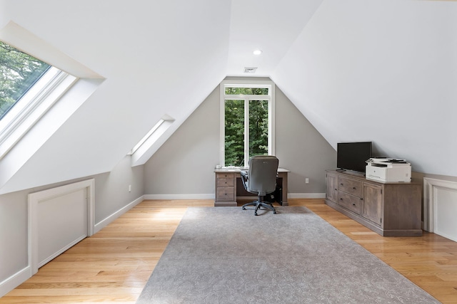 office area featuring light wood-type flooring and lofted ceiling with skylight