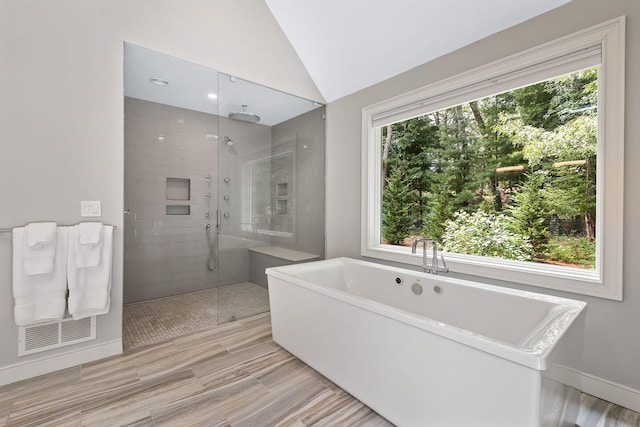 bathroom featuring lofted ceiling, plus walk in shower, and a wealth of natural light