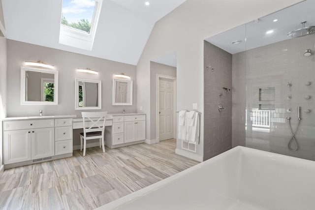 bathroom featuring tiled shower, vanity, and vaulted ceiling