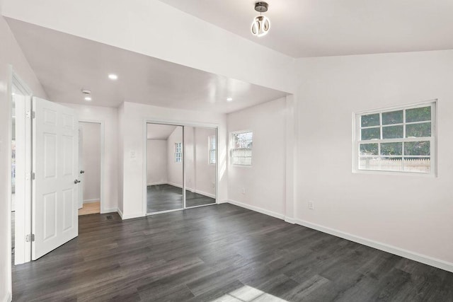 unfurnished bedroom featuring a closet, dark hardwood / wood-style floors, and multiple windows