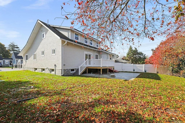 rear view of house featuring a wooden deck, a yard, and a patio