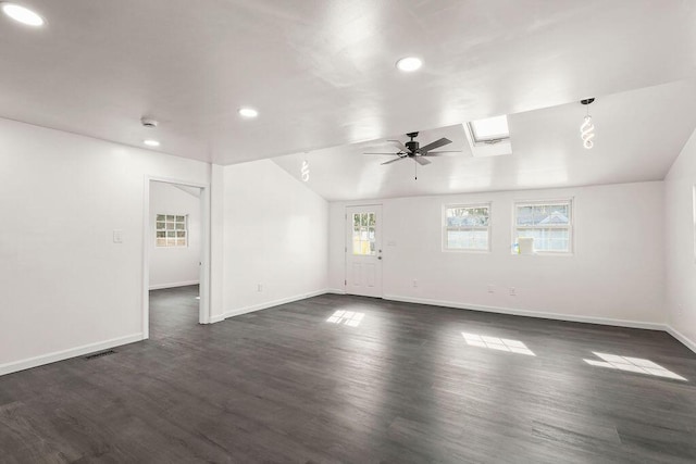 empty room with a healthy amount of sunlight, vaulted ceiling with skylight, and dark wood-type flooring