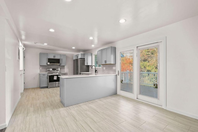 kitchen featuring kitchen peninsula, sink, gray cabinetry, and appliances with stainless steel finishes