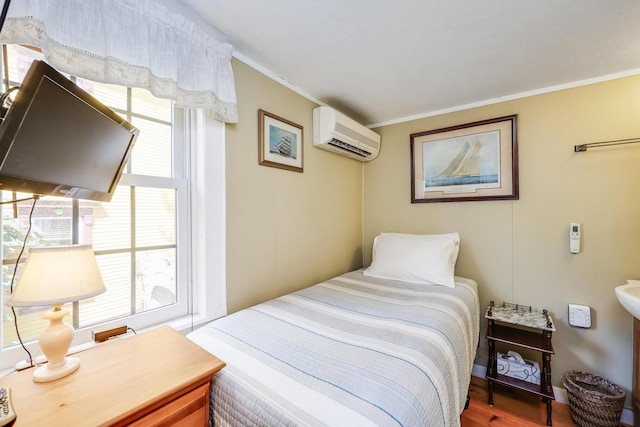 bedroom with a wall mounted AC, crown molding, and hardwood / wood-style floors