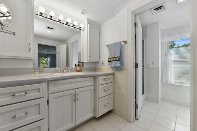 bathroom featuring tile patterned flooring, vanity, a wealth of natural light, and tile walls