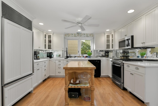 kitchen with light hardwood / wood-style floors, white cabinets, appliances with stainless steel finishes, and tasteful backsplash