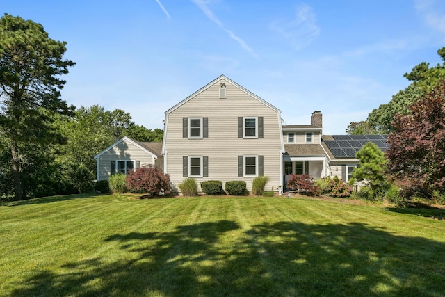 back of property with a lawn and solar panels