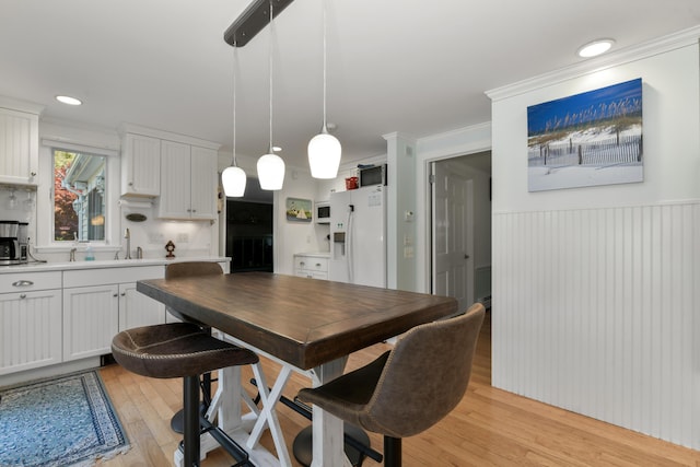 dining area featuring ornamental molding and light hardwood / wood-style floors