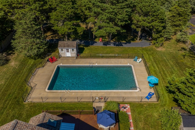 view of pool with a patio, a yard, and a storage shed