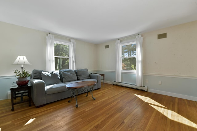 living room with hardwood / wood-style flooring, a healthy amount of sunlight, and a baseboard heating unit