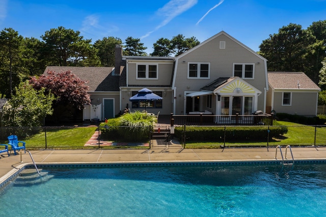 back of property featuring a fenced in pool and a lawn