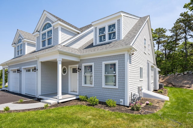 view of front of house with a garage, cooling unit, and a front yard