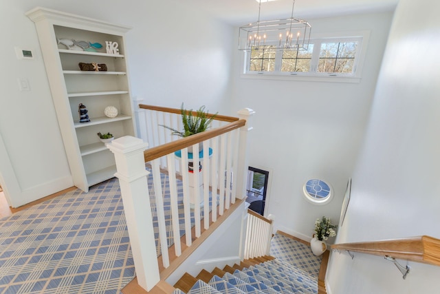 stairs with baseboards, a notable chandelier, and wood finished floors