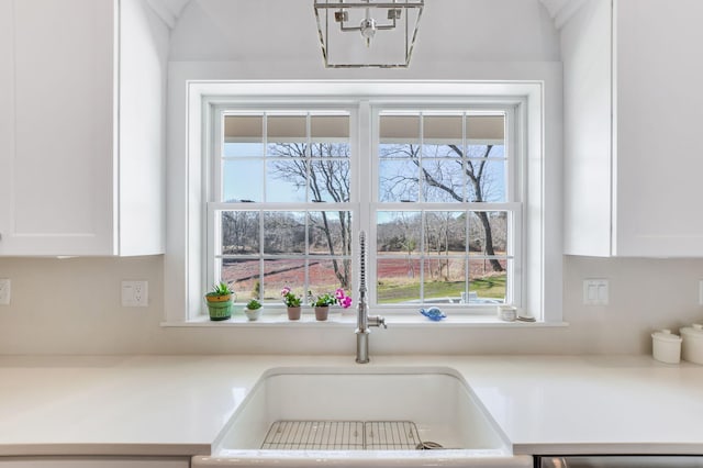 kitchen with white cabinetry, light countertops, a notable chandelier, and a sink