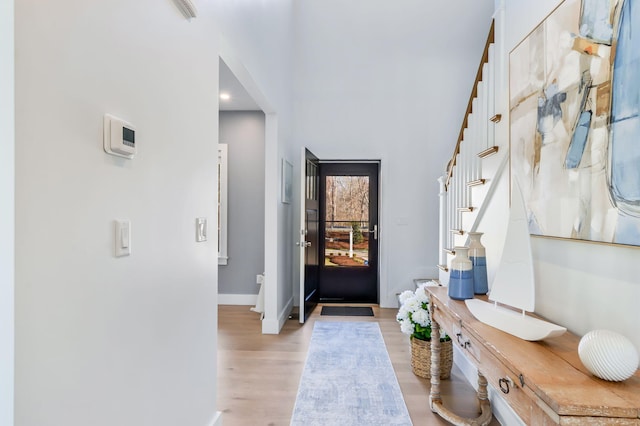 entryway featuring baseboards, light wood-style flooring, and stairway