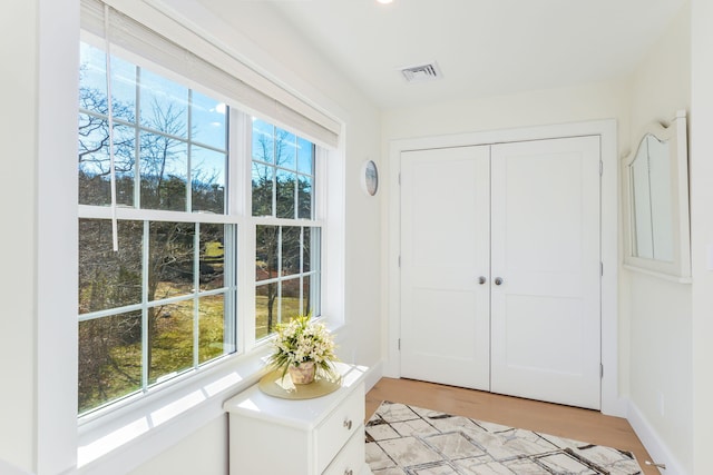entryway featuring baseboards, light wood finished floors, visible vents, and plenty of natural light