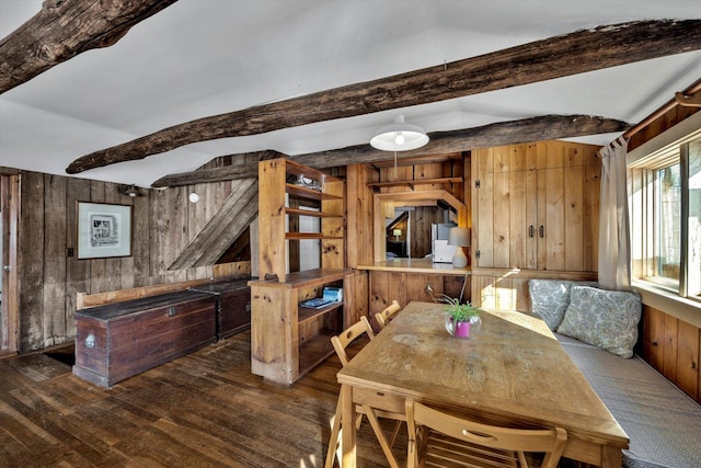 dining space featuring wood finished floors, wood walls, and beamed ceiling