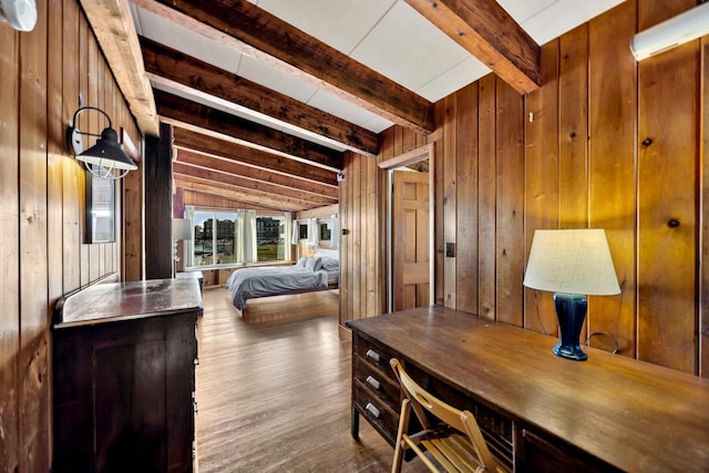 bedroom featuring wood walls, beam ceiling, and wood finished floors