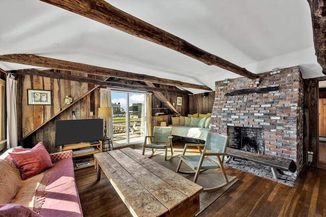 living area featuring wooden walls, a brick fireplace, wood-type flooring, and beam ceiling