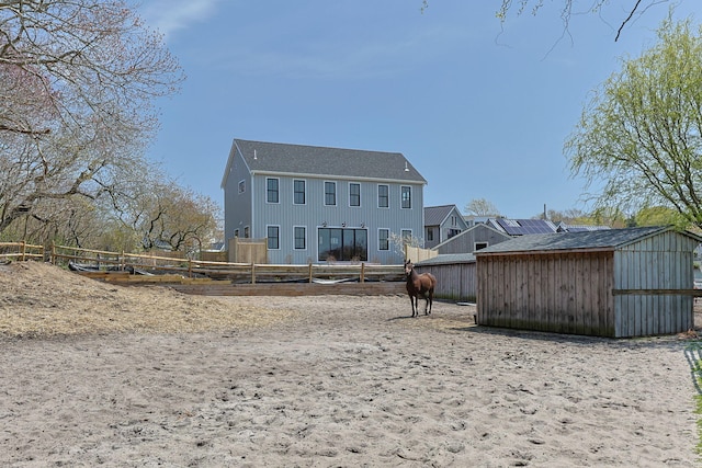 rear view of house with fence, an outbuilding, and a shed