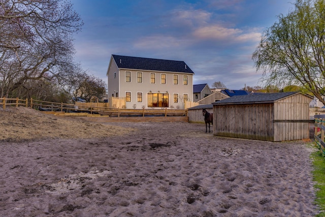 back of property with a fenced backyard, an outdoor structure, and a shed