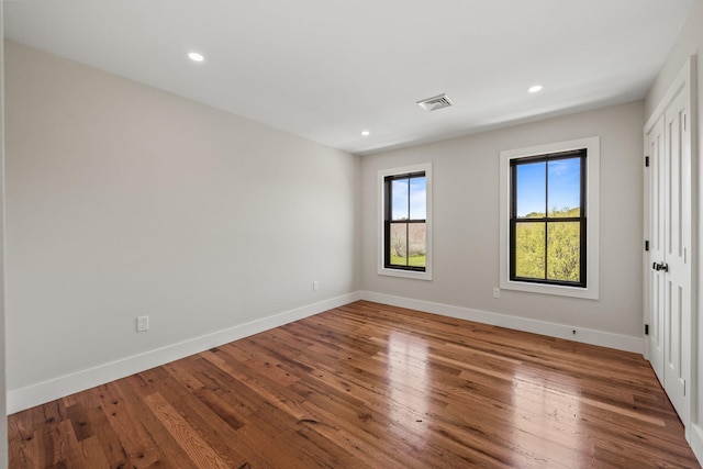 spare room with baseboards, wood finished floors, and recessed lighting