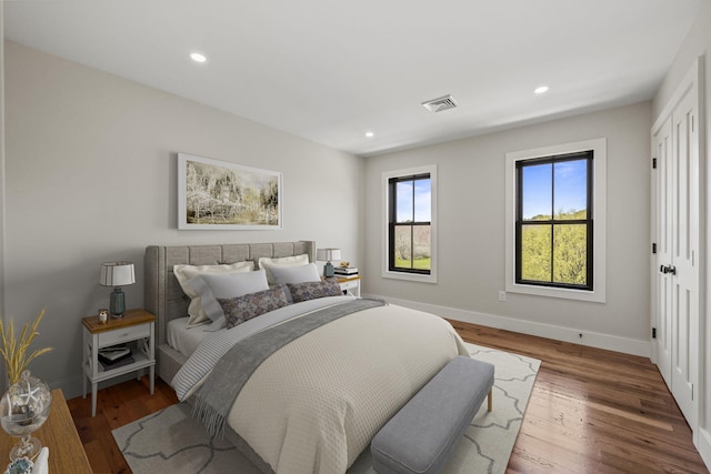 bedroom with baseboards, wood finished floors, and recessed lighting