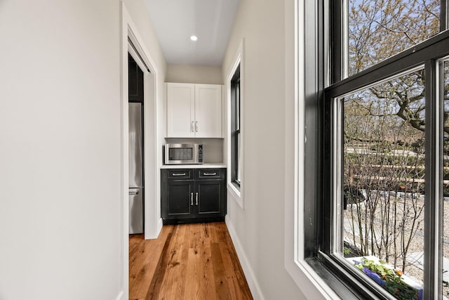 hallway featuring light wood-type flooring, baseboards, and recessed lighting