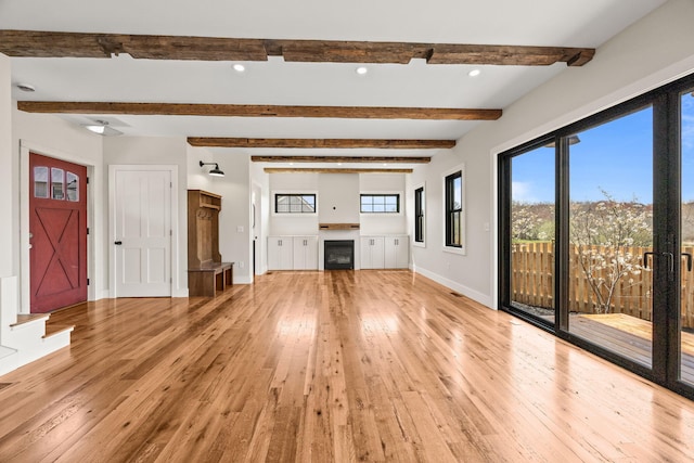 unfurnished living room featuring light wood-type flooring, baseboards, healthy amount of natural light, beam ceiling, and recessed lighting