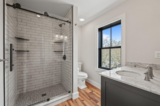 bathroom featuring wood finished floors, a shower stall, toilet, and baseboards