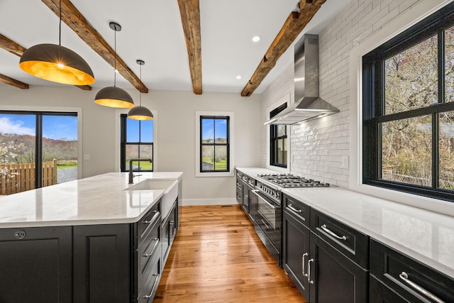 kitchen with high end stainless steel range oven, dark cabinets, wall chimney exhaust hood, baseboards, and beamed ceiling