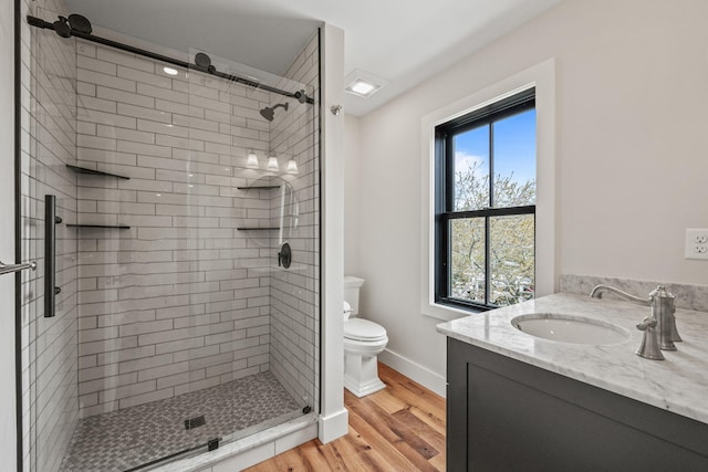 bathroom featuring wood finished floors, a shower stall, toilet, and baseboards
