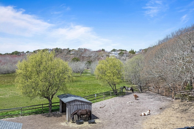 view of community featuring a view of rural / pastoral area, fence, and an outbuilding