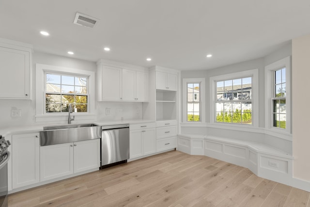 kitchen with visible vents, dishwasher, light wood-style floors, white cabinetry, and a sink