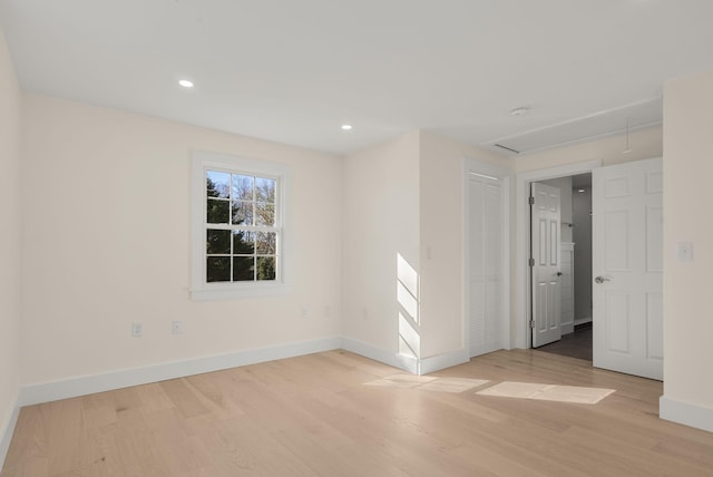 unfurnished room with recessed lighting, light wood-type flooring, attic access, and baseboards