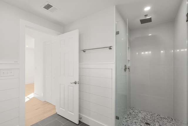 full bath featuring visible vents, tiled shower, and wood finished floors