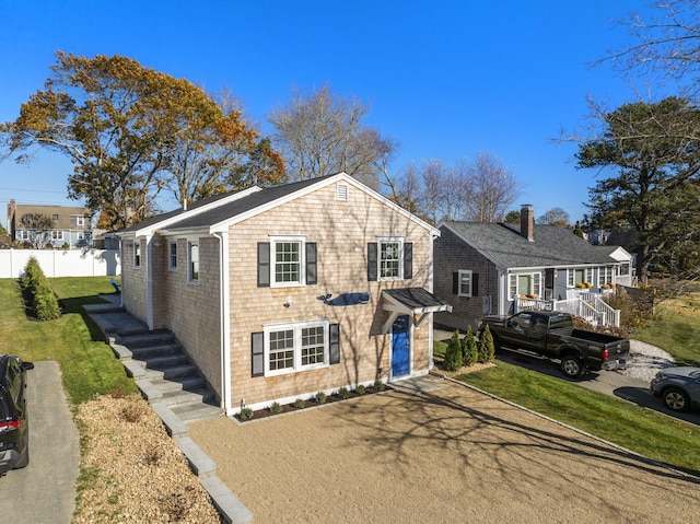 view of front of house featuring stairs, fence, and a front yard